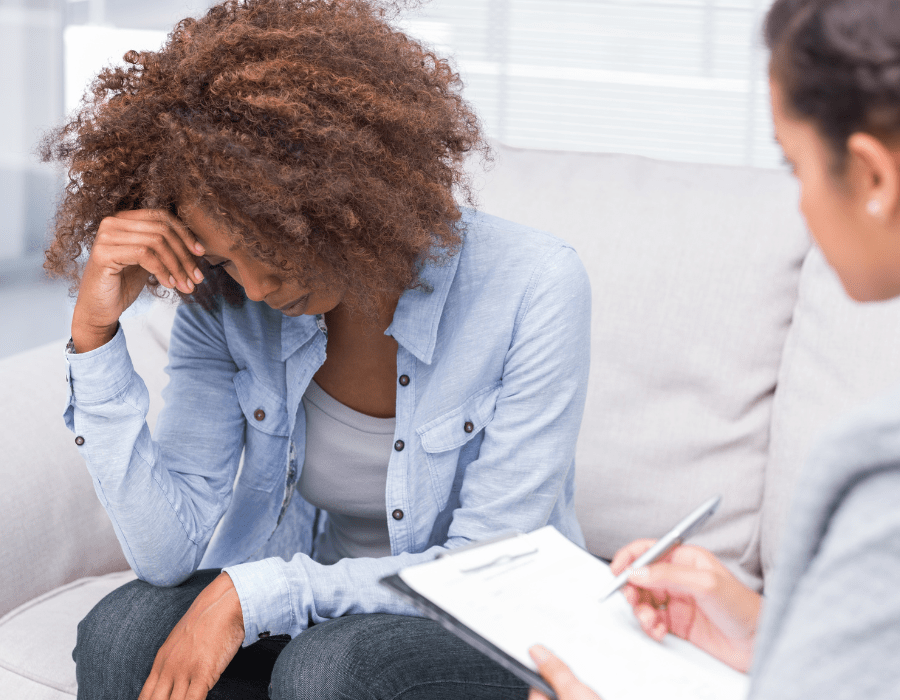 Woman sitting with her head down, in a supportive conversation
